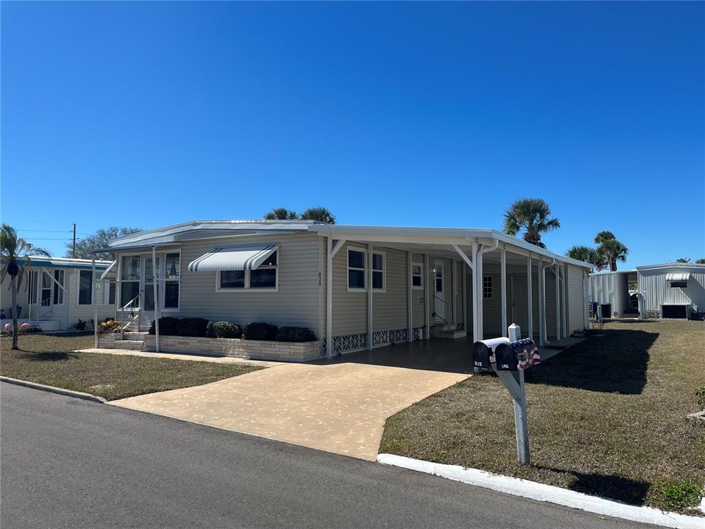 A light-colored mobile home features a carport, a concrete driveway, and a mailbox — 828 TRENTO, VENICE, FL