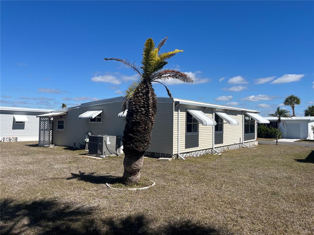 A single-story manufactured home with light siding and window awnings sits on a grassy lot — 828 TRENTO, VENICE, FL