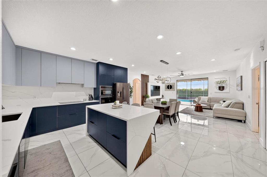 A modern open-concept kitchen and living area with navy and gray cabinets and marble flooring — 3016 CAMINO REAL DRIVE S, KISSIMMEE, FL