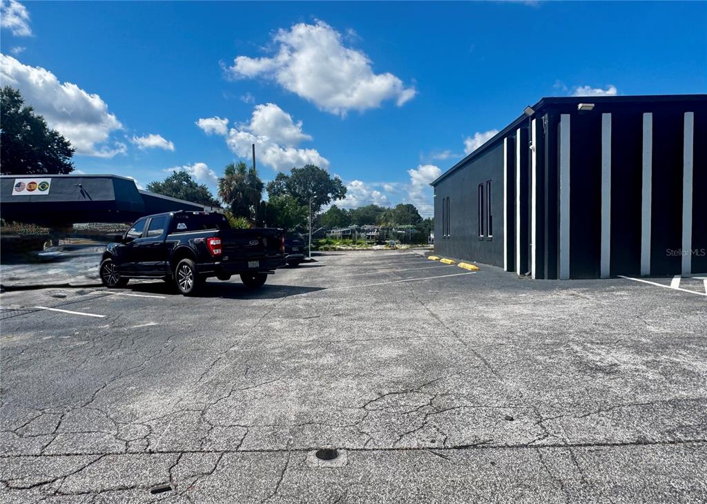 A black pickup truck is parked in an asphalt lot next to a black building — 120 W CARROLL STREET, KISSIMMEE, FL
