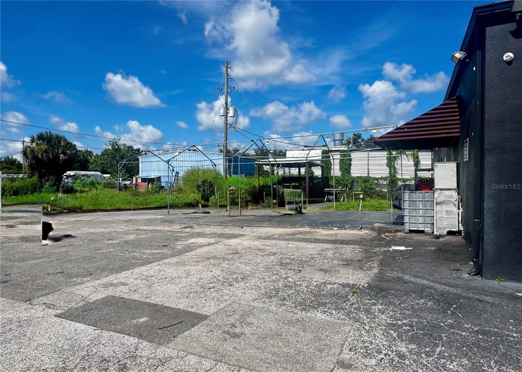 An outdoor paved lot features a metal frame structure and a building with an awning — 120 W CARROLL STREET, KISSIMMEE, FL