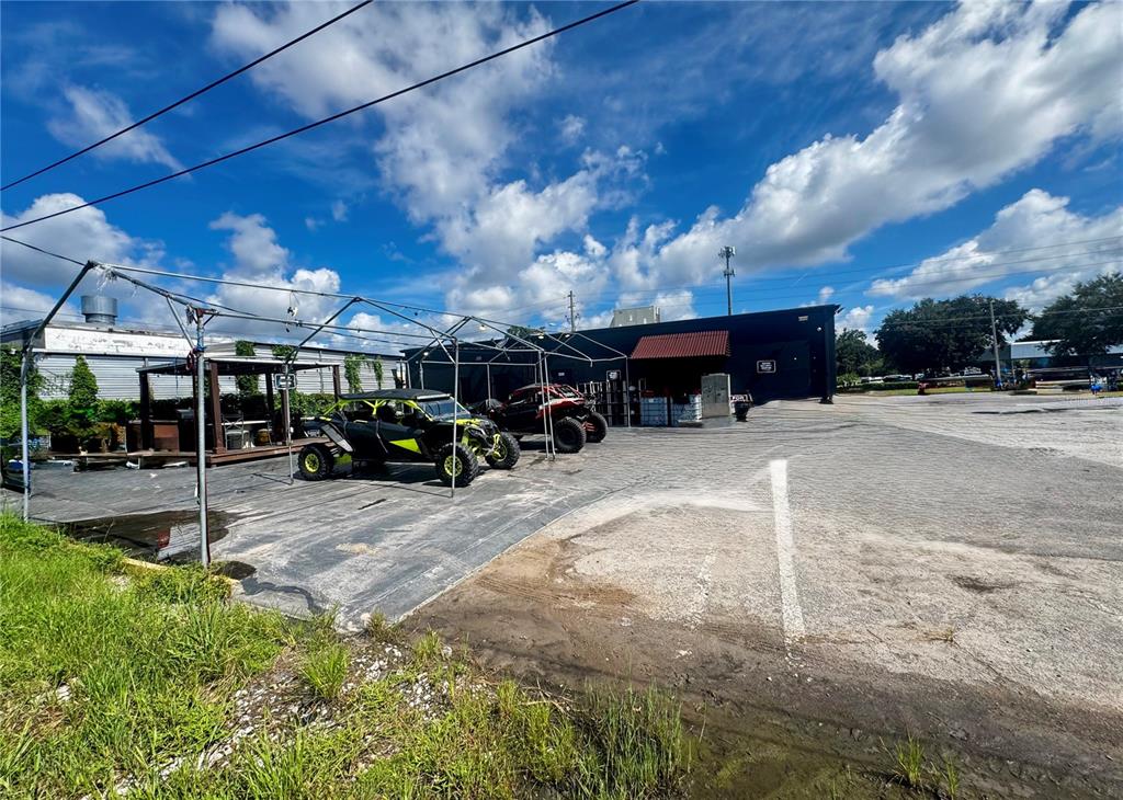 An outdoor parking lot features two off-road vehicles parked under a metal frame structure — 120 W CARROLL STREET, KISSIMMEE, FL