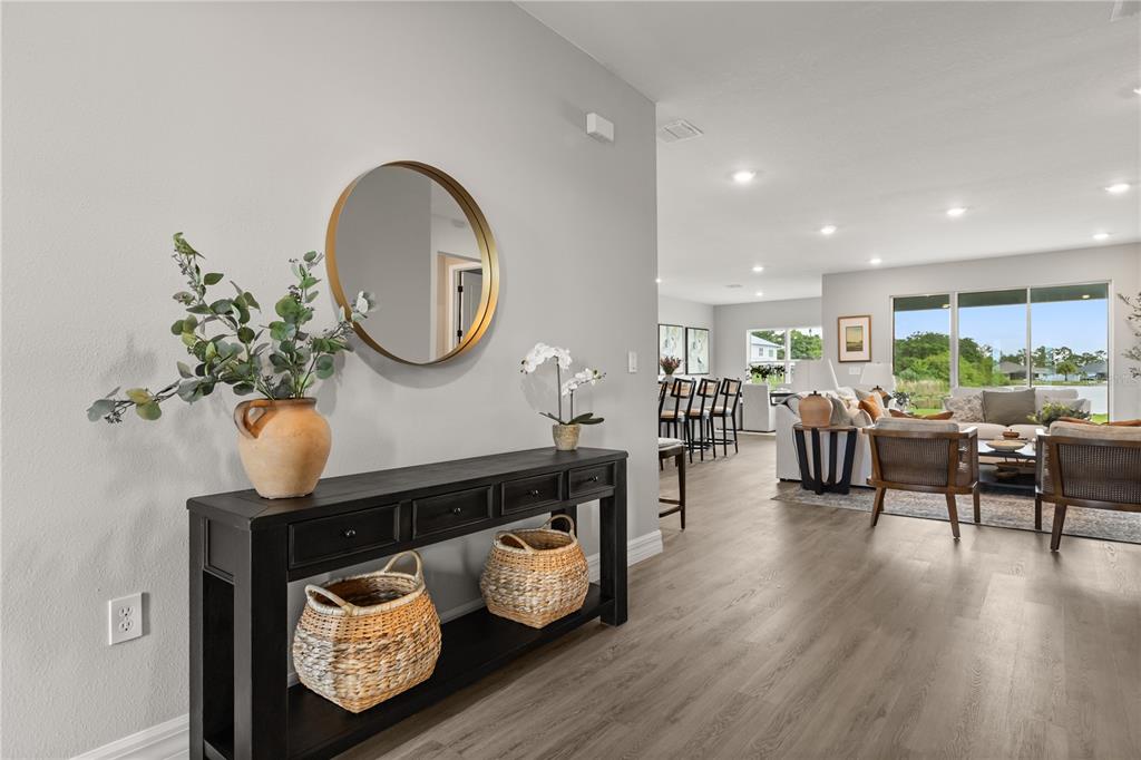 A foyer features a black console table with baskets beneath a round gold-framed mirror — 6400 SUN N LAKE BOULEVARD, SEBRING, FL