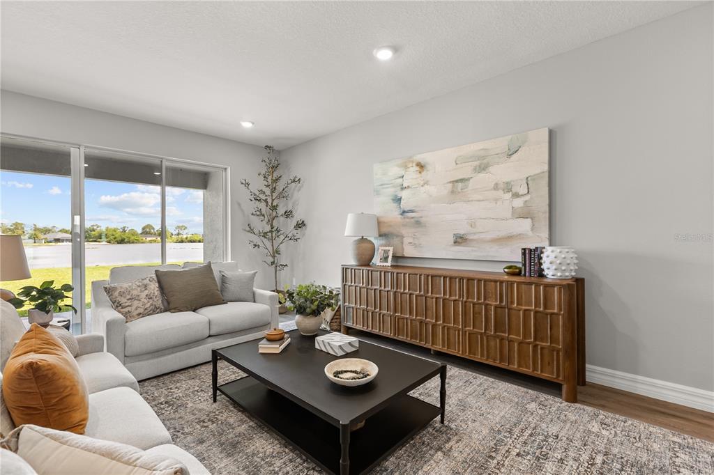 A living room features a sofa, coffee table, wooden console, and a view of water — 6400 SUN N LAKE BOULEVARD, SEBRING, FL