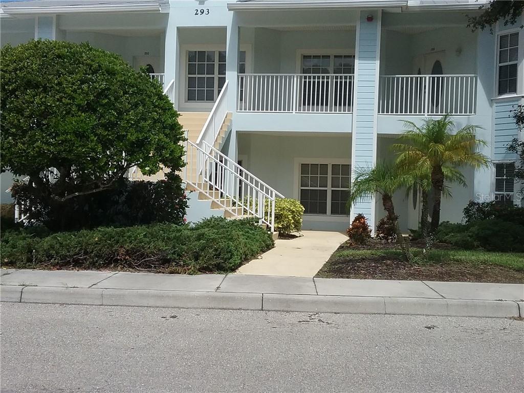 A two-story residential building features a white staircase leading to an upper-level balcony — 293 HIDDEN BAY DRIVE UNIT 203, OSPREY, FL
