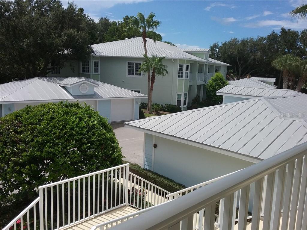 An elevated view shows light green multi-story buildings with metal roofs and white railings — 293 HIDDEN BAY DRIVE UNIT 203, OSPREY, FL