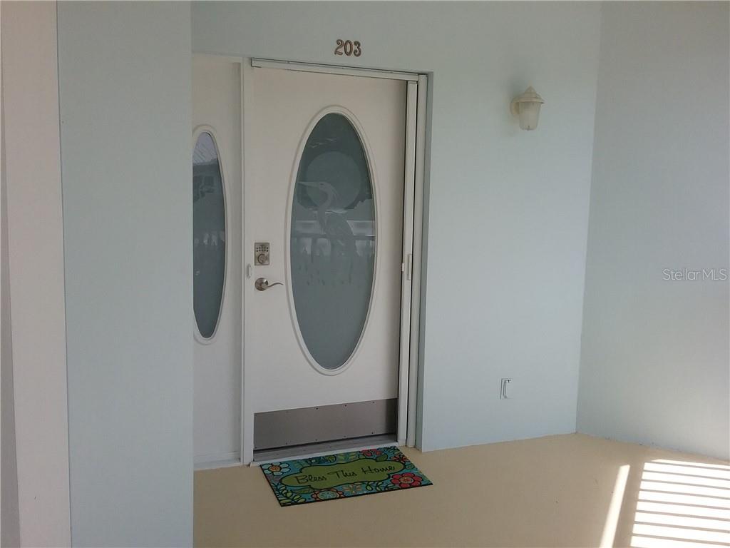 A white front door with an oval glass insert and a welcome mat — 293 HIDDEN BAY DRIVE UNIT 203, OSPREY, FL