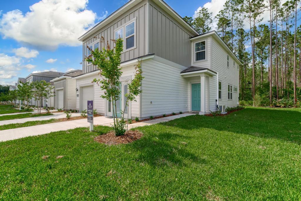 A two-story house with light-colored siding, a teal front door, and a small front yard — 10731 WATERFIELD ROAD, JACKSONVILLE, FL