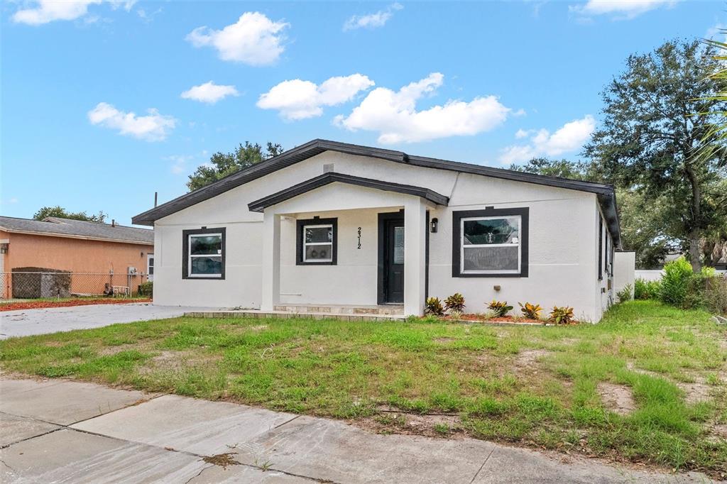 A single-story white house with a dark roof and black window trim under a blue sky — 2312 22ND AVENUE SW, LARGO, FL