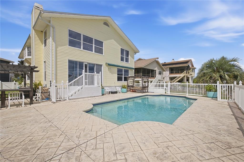 A yellow two-story house features a backyard swimming pool with a stamped concrete patio — 6244 SPOONBILL DRIVE, NEW PORT RICHEY, FL