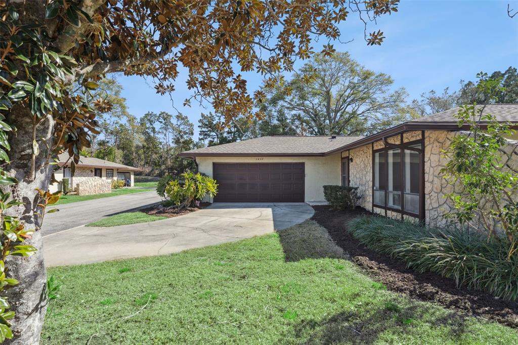 A single-story house with a stone facade, brown garage door, and a concrete driveway — 1457 MAGELLAN CIRCLE UNIT 1003, ORLANDO, FL