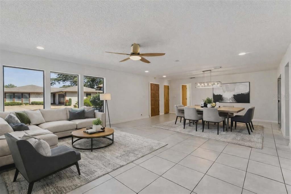 A bright open-concept living and dining area with tile floors and large windows — 1457 MAGELLAN CIRCLE UNIT 1003, ORLANDO, FL