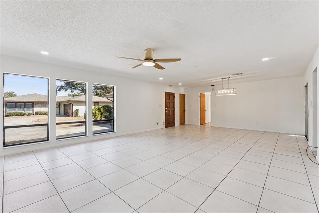 A spacious, white-tiled living area features a ceiling fan, recessed lighting, and large windows — 1457 MAGELLAN CIRCLE UNIT 1003, ORLANDO, FL