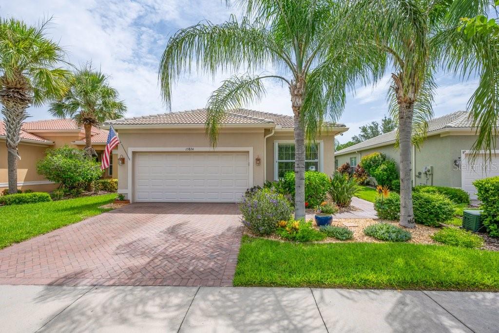 A single-story house with a brick driveway, palm trees, and a two-car garage — 15824 AMBER FALLS DRIVE, WIMAUMA, FL