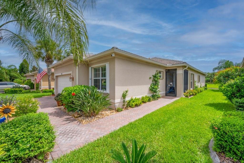 A single-story house with a beige stucco exterior, a paved walkway, and a manicured lawn — 15824 AMBER FALLS DRIVE, WIMAUMA, FL