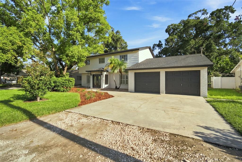 A two-story house with a white exterior, dark garage doors, and a concrete driveway — 2705 SILVER LAKE AVENUE, TAMPA, FL