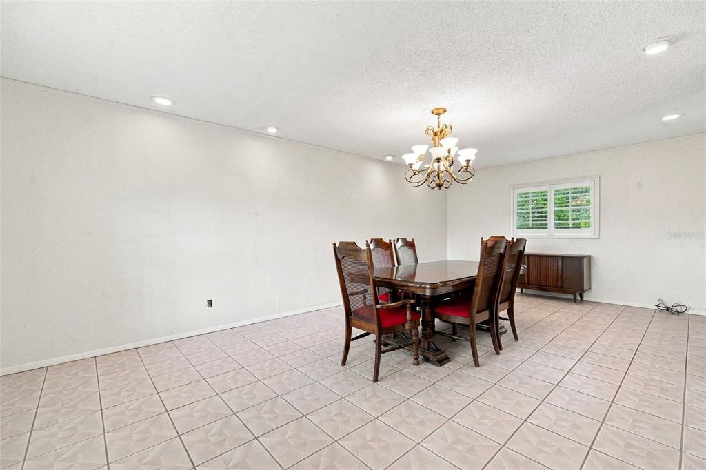A dining room features a wooden table with six chairs, a chandelier, and tiled flooring — 2705 SILVER LAKE AVENUE, TAMPA, FL