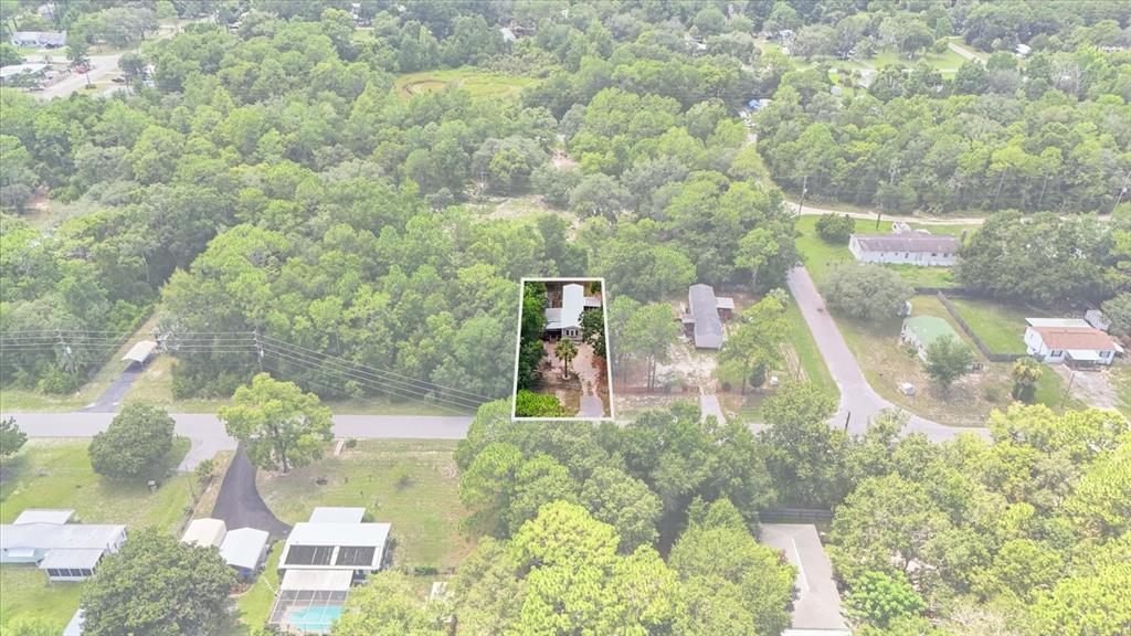 An aerial view shows a single-story house highlighted within a wooded residential neighborhood — 3496 S ARUNDEL TERRACE, HOMOSASSA, FL