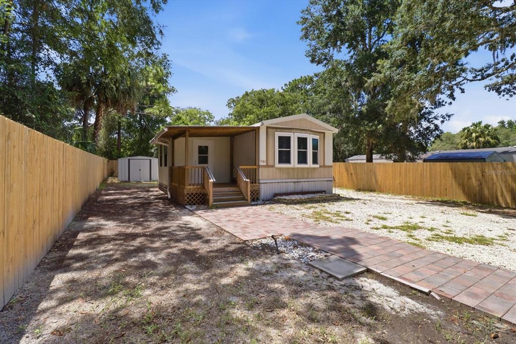 A single-story mobile home with a wooden porch and a brick walkway in a fenced yard — 3496 S ARUNDEL TERRACE, HOMOSASSA, FL