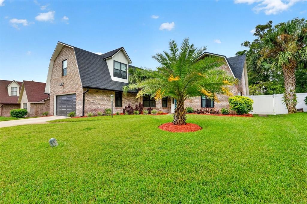 A brick house with a dark shingled roof, a garage, and a palm tree in front — 3 FOX HOLLOW DRIVE, ORMOND BEACH, FL