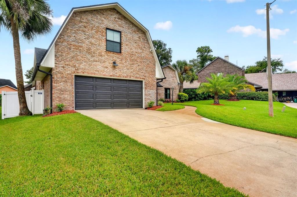 A brick garage with a gambit roof and a concrete driveway sits on a grassy lawn — 3 FOX HOLLOW DRIVE, ORMOND BEACH, FL