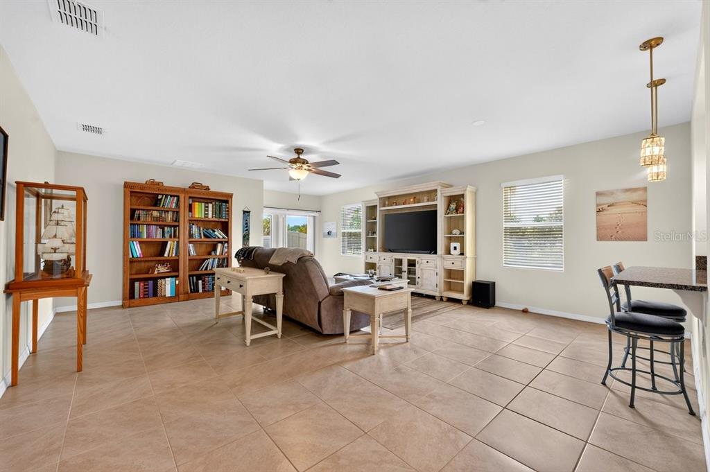 A living room features tile flooring, a large entertainment center, a bookshelf, and a ceiling fan — 5349 SANDPINE HAVEN LANE, PORT ORANGE, FL