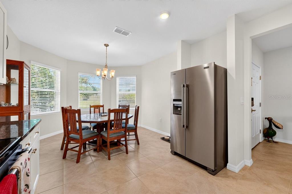 A kitchen and dining area featuring tile floors, a stainless steel refrigerator, and a wooden table — 5349 SANDPINE HAVEN LANE, PORT ORANGE, FL