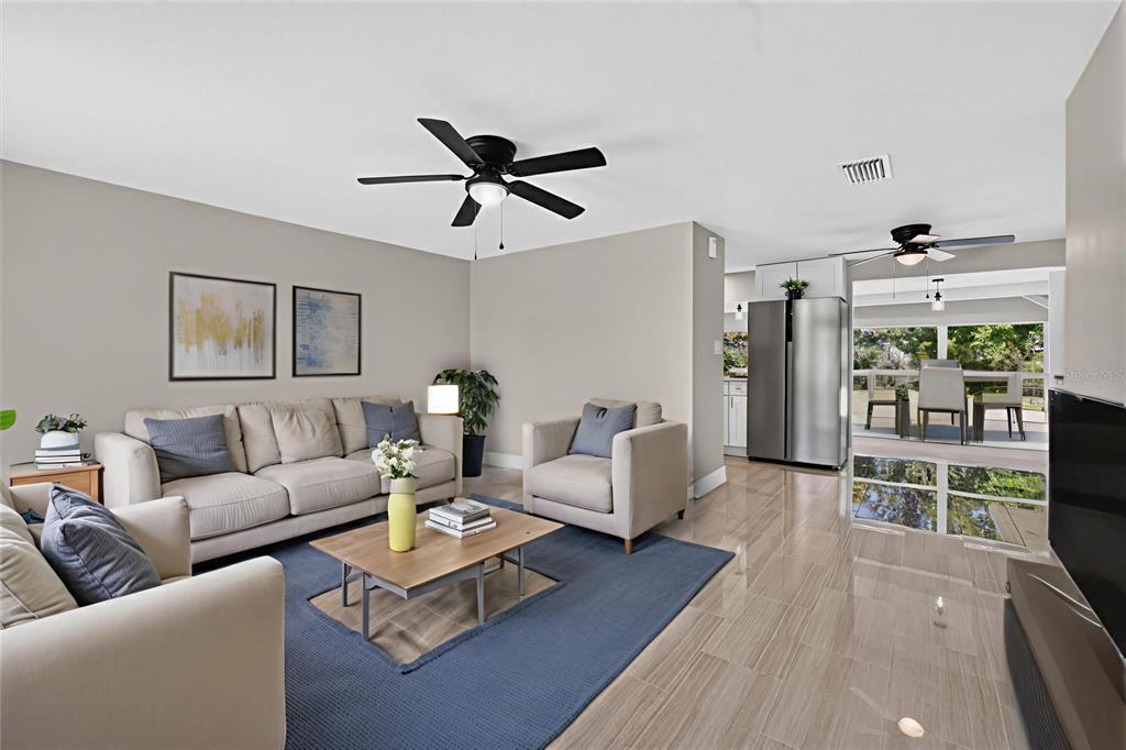 A living room with light tile floors, a blue area rug, and neutral-toned furniture — 312 READING STREET NW, PORT CHARLOTTE, FL