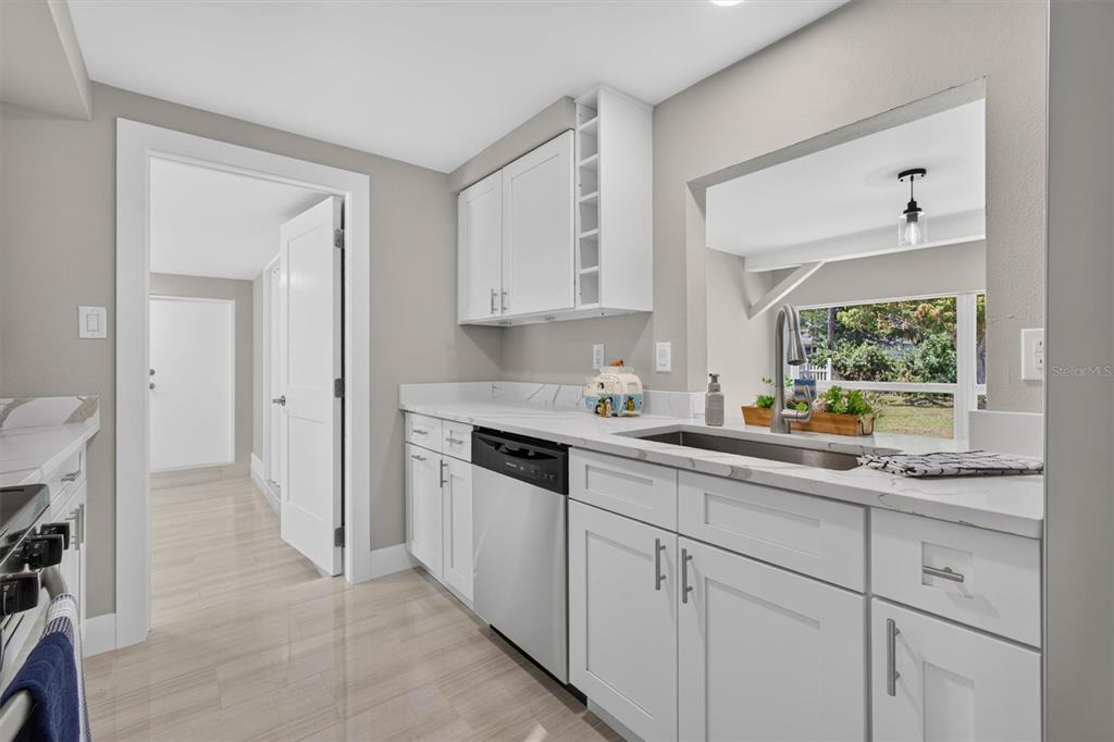 A modern kitchen features white cabinets, stainless steel appliances, and a window overlooking the yard — 312 READING STREET NW, PORT CHARLOTTE, FL