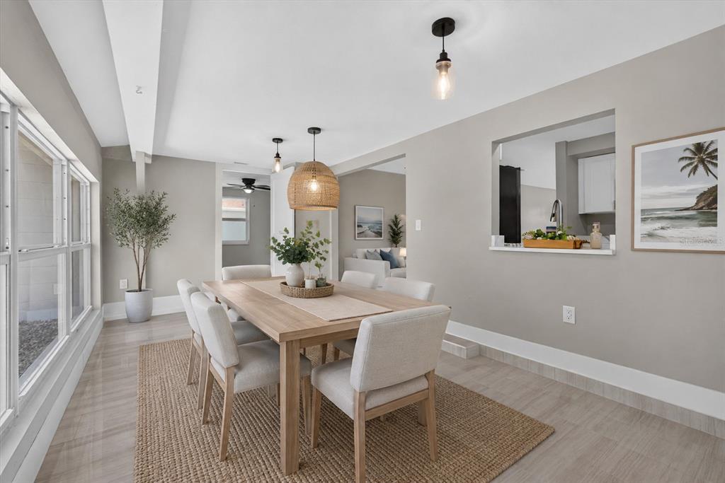 A dining room features a wooden table, light-colored chairs, a woven rug, and pendant lighting — 312 READING STREET NW, PORT CHARLOTTE, FL