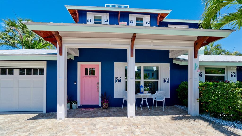 A blue house exterior features a bright pink front door and a covered brick porch — 522 68TH STREET, HOLMES BEACH, FL