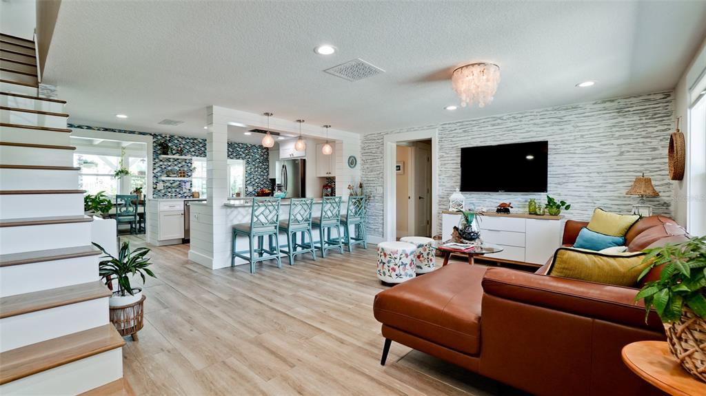 An open-concept living room and kitchen featuring wood-look flooring, a leather sofa, and bar seating — 522 68TH STREET, HOLMES BEACH, FL