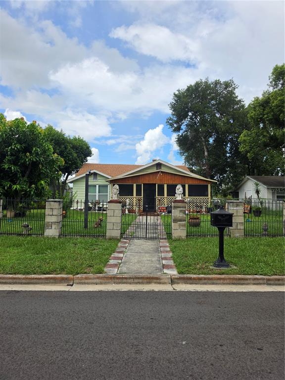 A single-story house with a screened front porch, fenced yard, and two decorative lion statues — 515 N 3RD STREET, LAKE WALES, FL