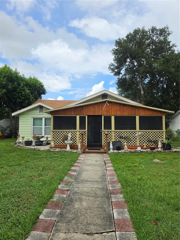 A single-story house with a light green exterior and a front screened-in wooden porch — 515 N 3RD STREET, LAKE WALES, FL