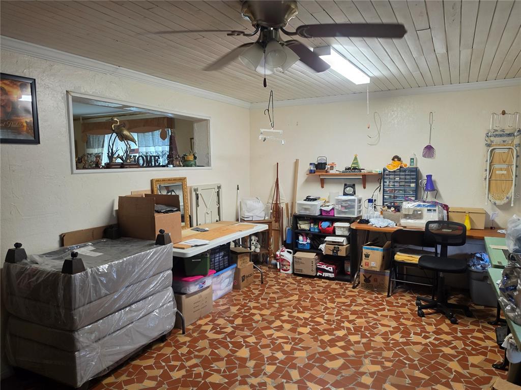 A cluttered utility room features a ceiling fan, a pass-through window, and patterned tile flooring — 515 N 3RD STREET, LAKE WALES, FL