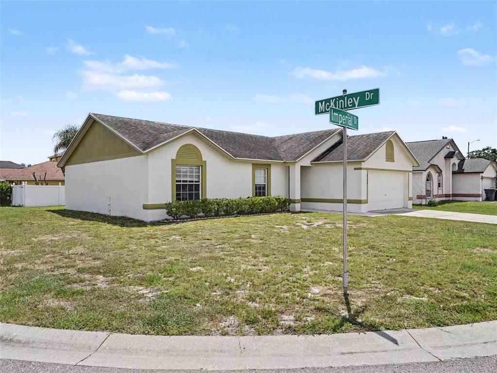 A single-story house with a white stucco exterior and a two-car garage on a corner — 3735 IMPERIAL DRIVE, WINTER HAVEN, FL