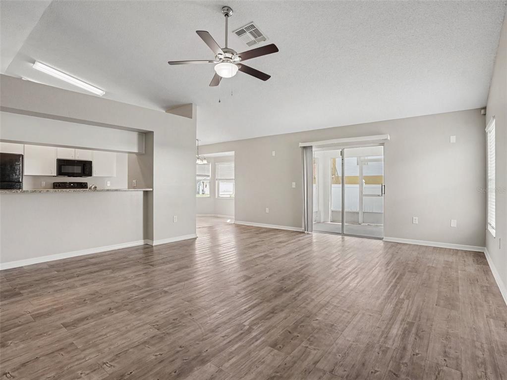 A living room with wood-look flooring, a ceiling fan, and an open kitchen pass-through — 3735 IMPERIAL DRIVE, WINTER HAVEN, FL