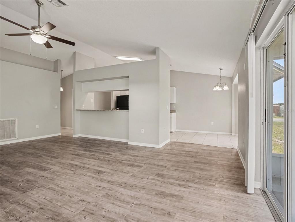 A living room with wood-look flooring, a ceiling fan, and an open kitchen pass-through — 3735 IMPERIAL DRIVE, WINTER HAVEN, FL