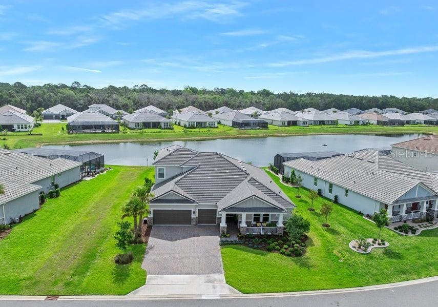 An aerial view shows a suburban house with a gray roof, garage, and backyard pond — 1369 ARKLOW CIRCLE, ORMOND BEACH, FL