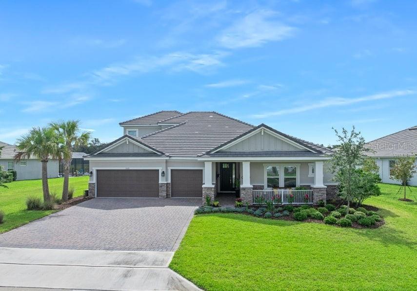 A single-story house with a two-car garage, a covered front porch, and a paved driveway — 1369 ARKLOW CIRCLE, ORMOND BEACH, FL
