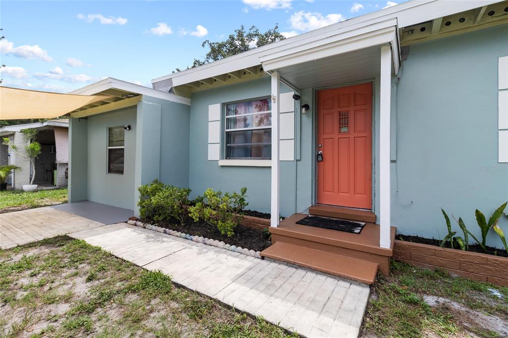 The exterior of a light blue house features a coral-colored front door and a walkway — 5410 14TH AVENUE S, GULFPORT, FL