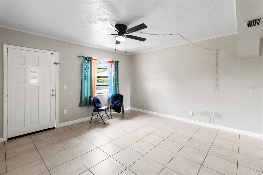 A room with light-colored tile flooring, a ceiling fan, and a white entry door — 5410 14TH AVENUE S, GULFPORT, FL