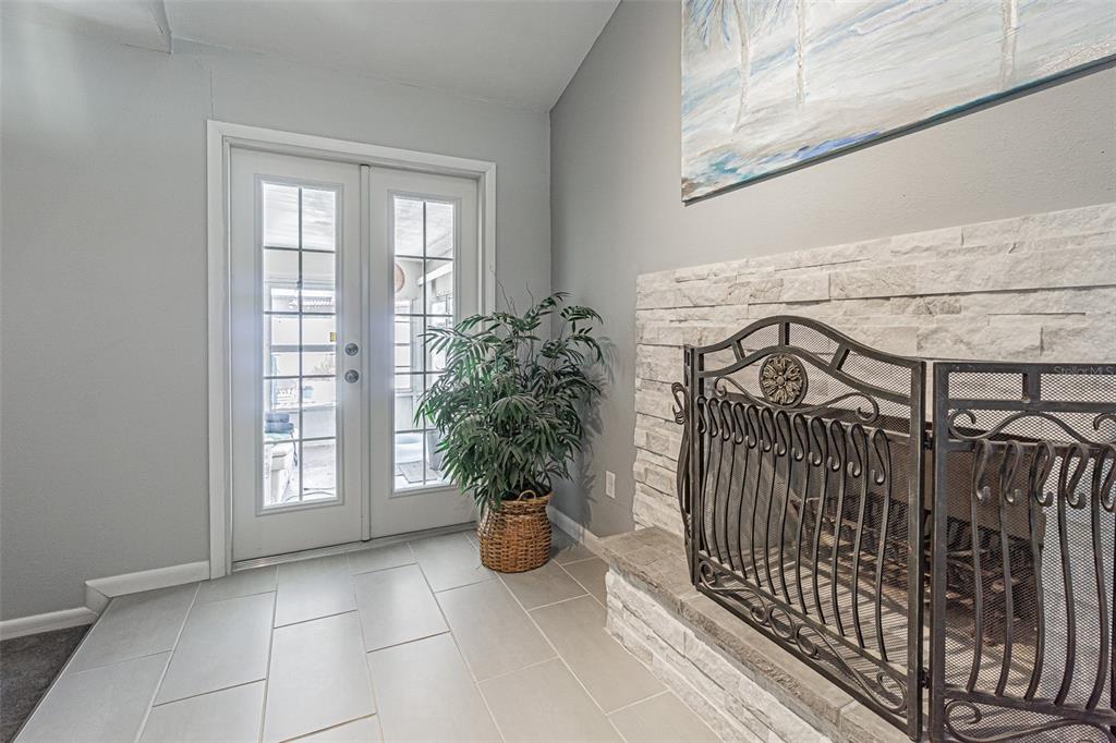 A room features light gray walls, tile flooring, a stone fireplace, and double glass doors — 7348 BROOKVIEW CIRCLE, TAMPA, FL