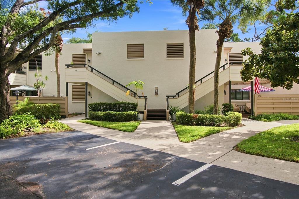 An exterior view of a two-story apartment building with outdoor staircases and a parking lot — 150 PINEHURST DRIVE UNIT 150, BRADENTON, FL