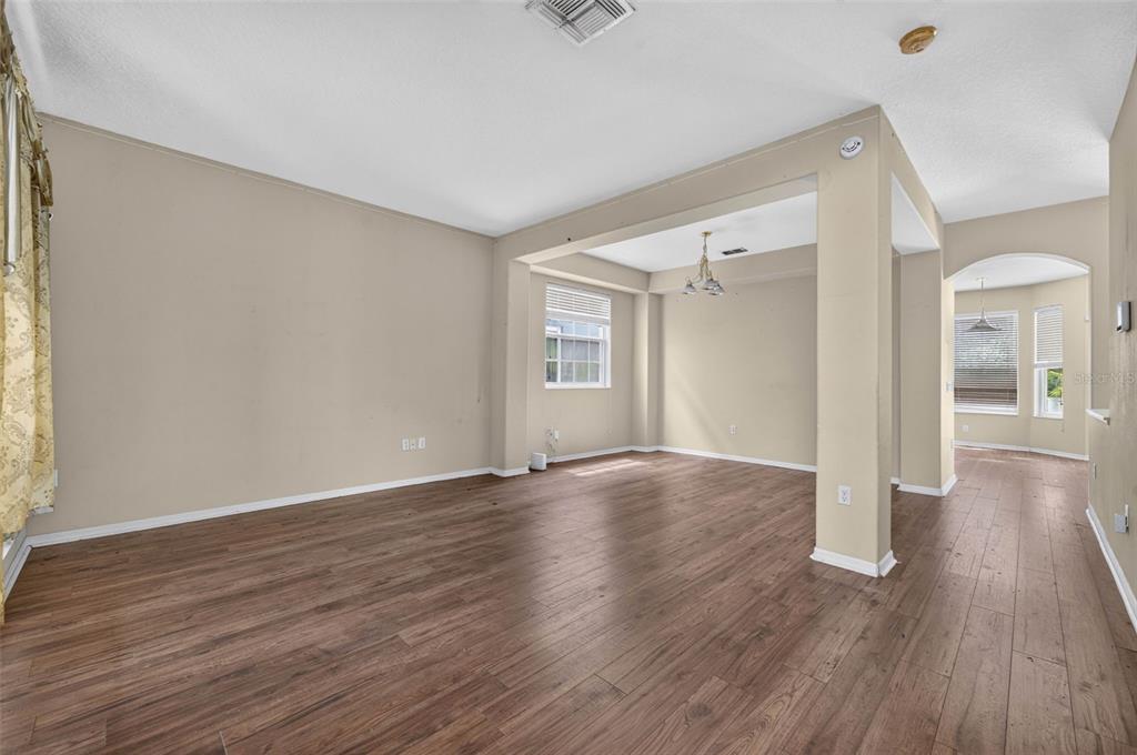 An empty living area with light-colored walls, wood-look flooring, and an open floor plan — 13026 MOSS PARK RIDGE DRIVE, ORLANDO, FL