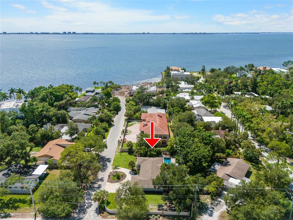 An aerial view shows a residential neighborhood with houses, lush trees, and a large bay — 771 INDIAN BEACH CIRCLE, SARASOTA, FL