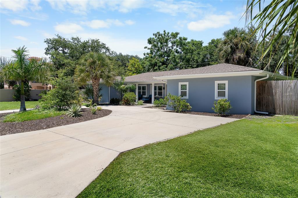 A single-story house with a gray exterior, a concrete driveway, and a manicured lawn — 771 INDIAN BEACH CIRCLE, SARASOTA, FL