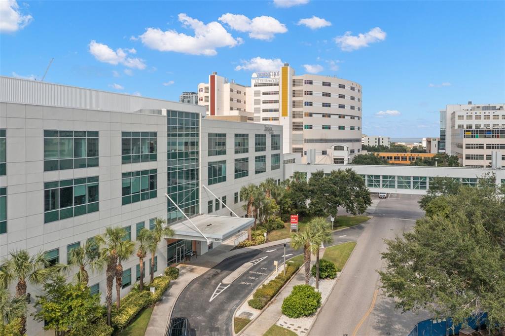 An exterior view of a multi-story office building with a covered entrance and skywalk — 625 6TH AVENUE S UNIT 405, ST PETERSBURG, FL