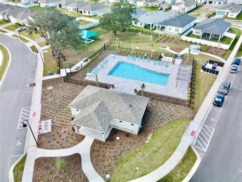 An aerial view shows a community swimming pool and clubhouse surrounded by residential homes — 5820 ARBORETUM STREET, ST CLOUD, FL