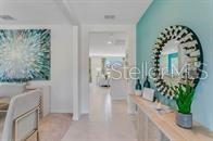 A hallway features a large round mirror on a teal wall and abstract wall art — 5820 ARBORETUM STREET, ST CLOUD, FL